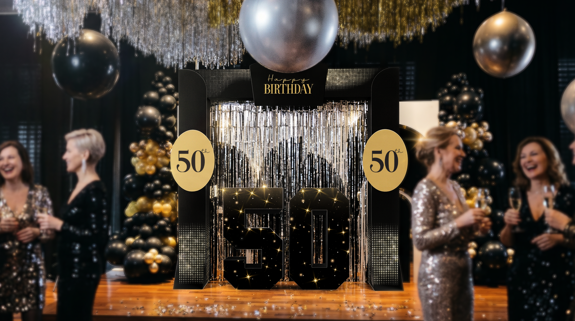 Decorative setup for a 50th birthday party with balloons and people in formal attire.